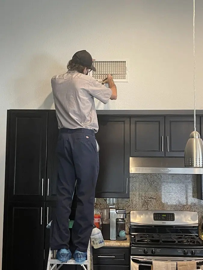 Technician inspecting an air vent during HVAC service in Royalton